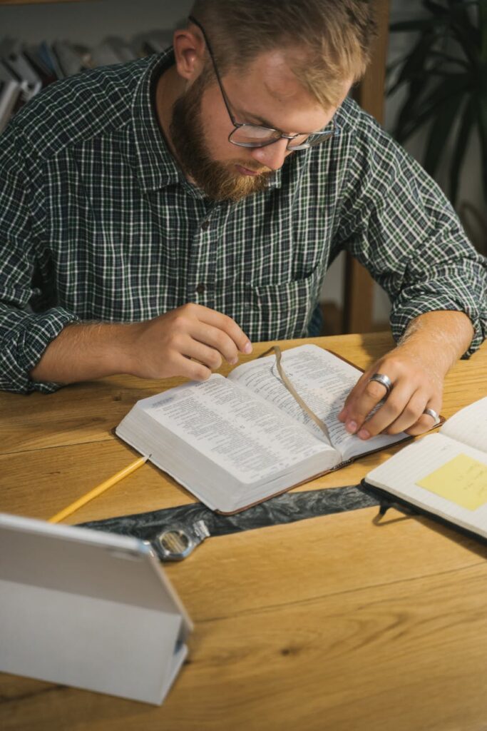 Bearded man attentively reading the Bible indoors, emphasizing faith and contemplation.
